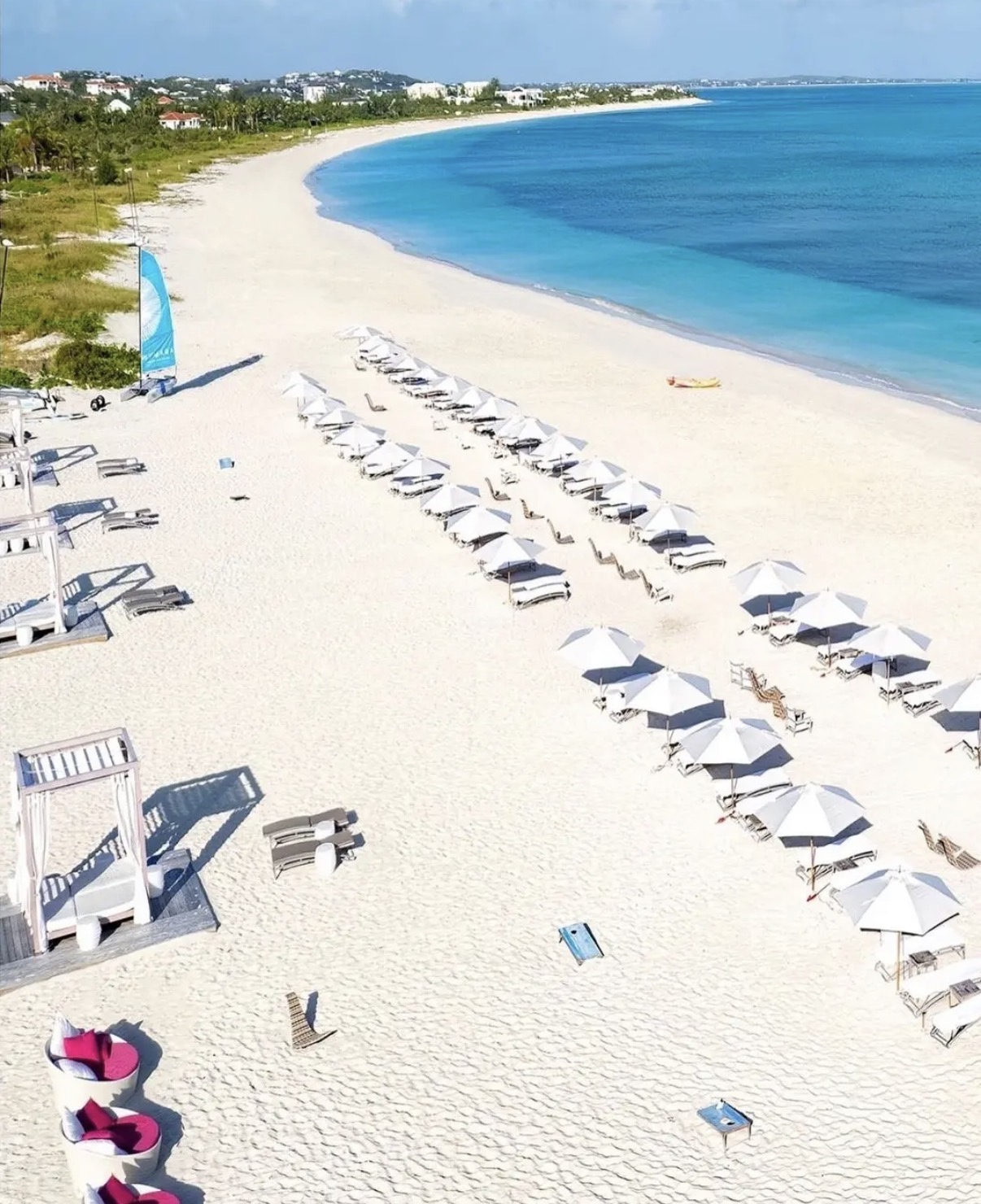 Aerial view of Grace Bay Beach with white umbrellas, loungers and turquoise water