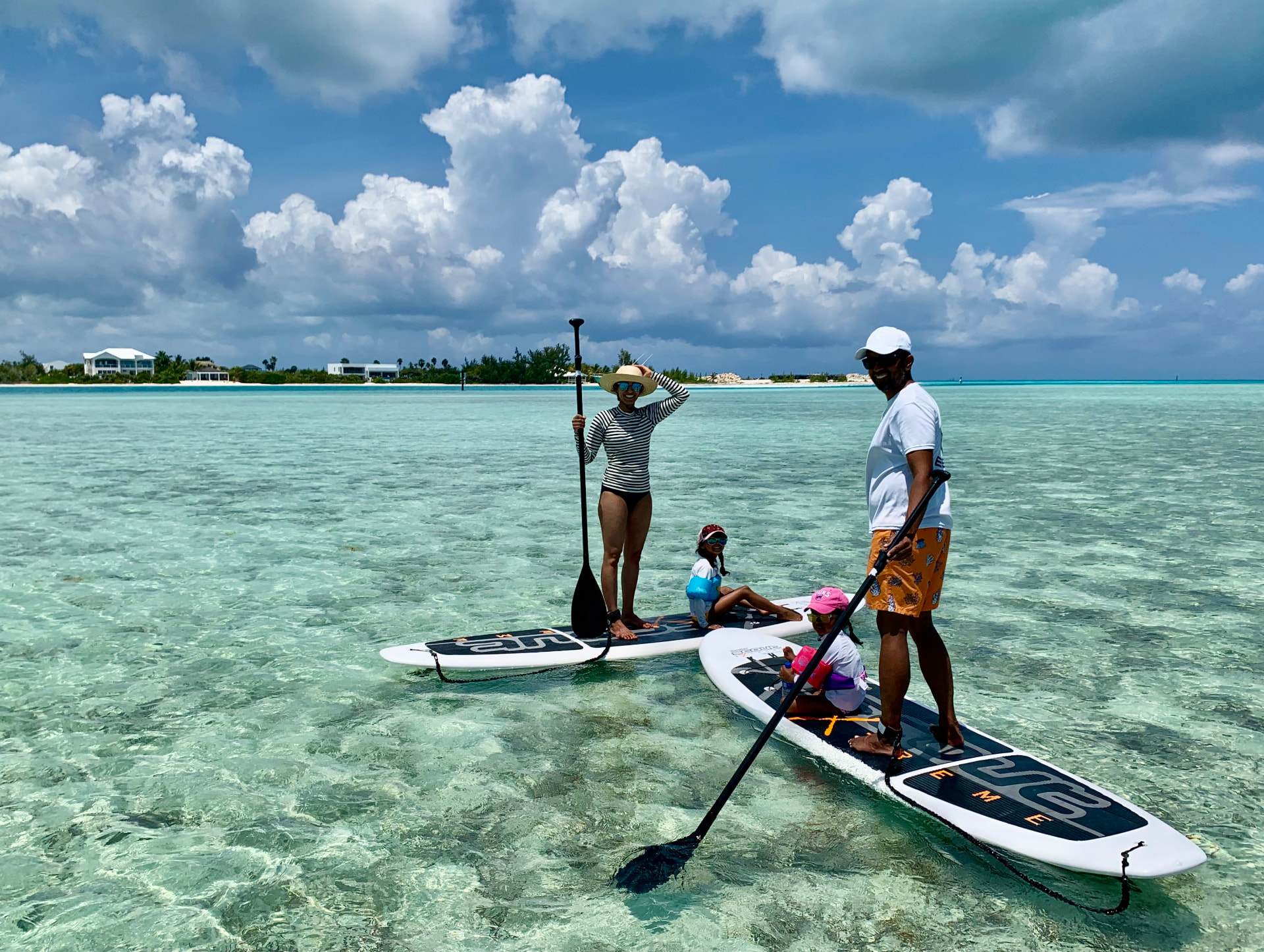 Family paddleboarding the shallow turquoise flats of Turks and Caicos