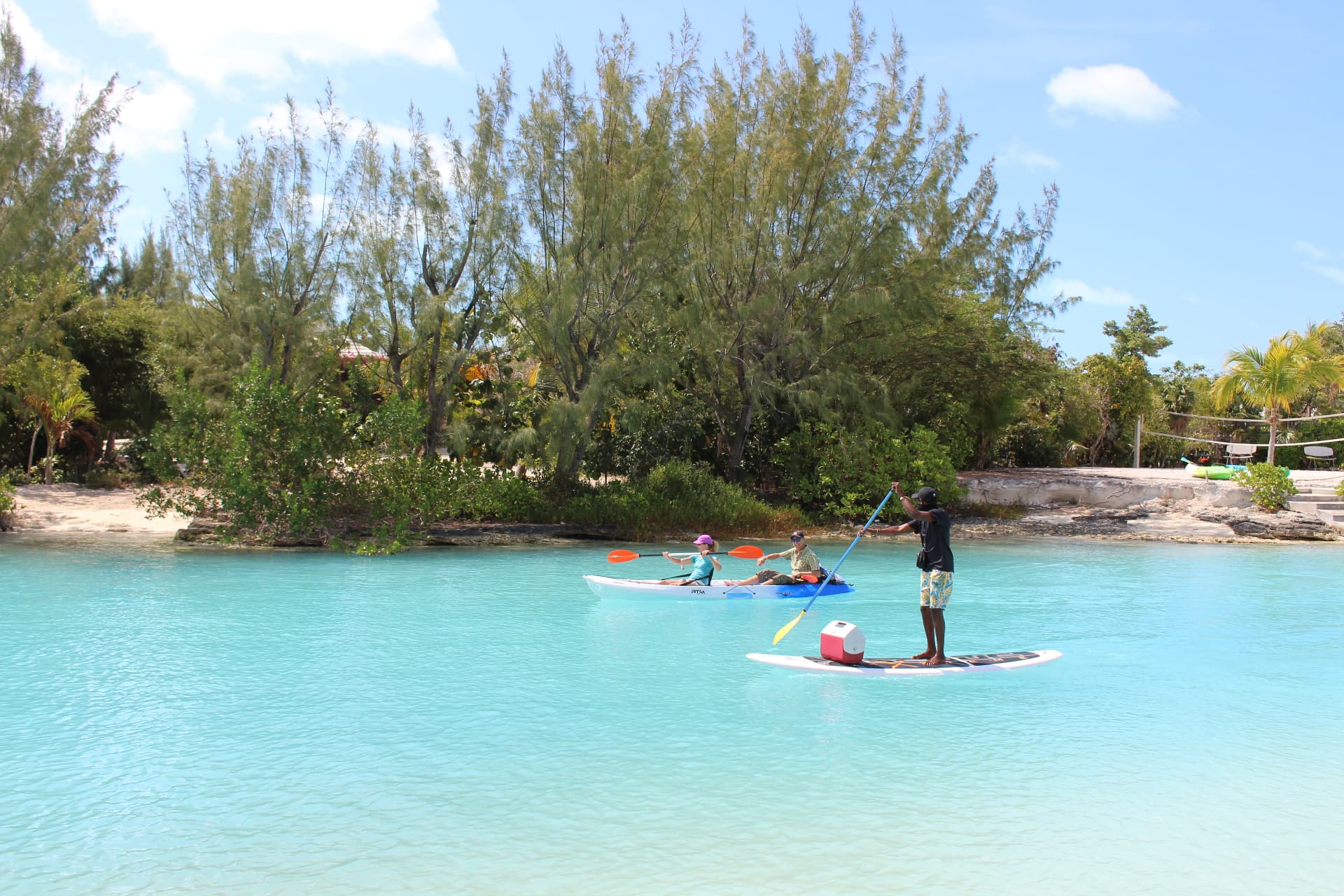 Guests kayaking and paddleboarding a calm turquoise lagoon